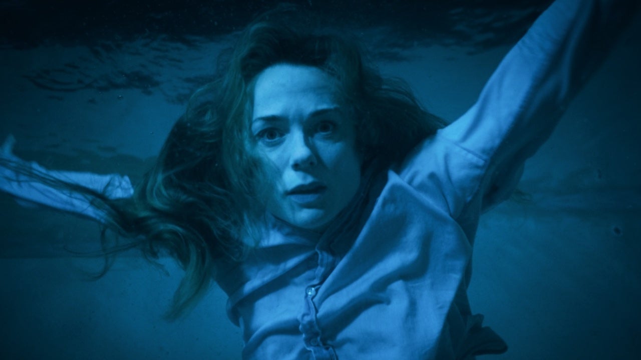Blue image of a woman swimming a pool wearing a button down shirt.